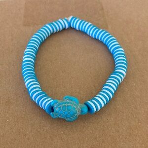 This is a clay bead with blue and white with a turtle charm